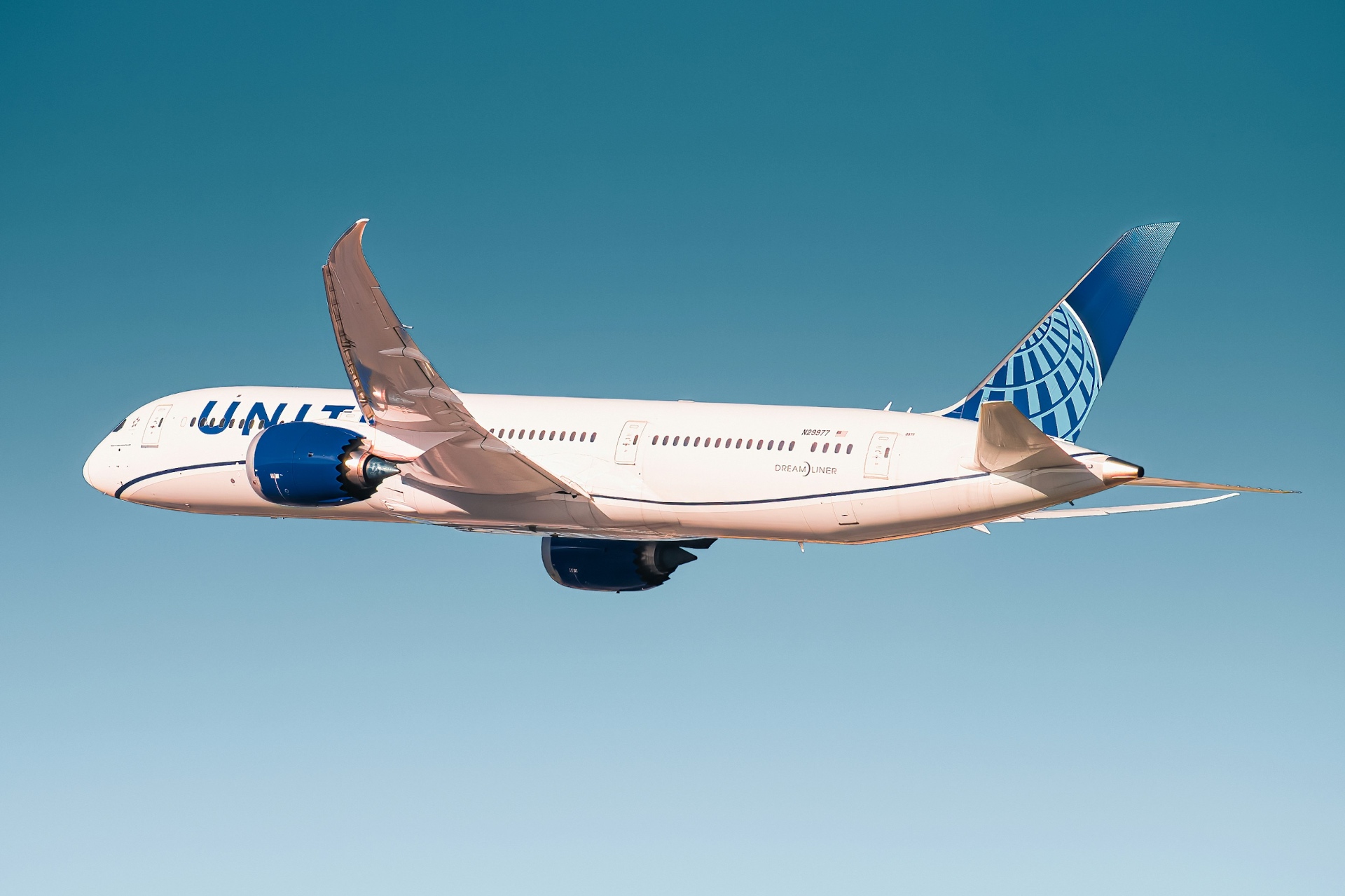 United Airlines Boeing 787 Dreamliner in flight against a clear blue sky.